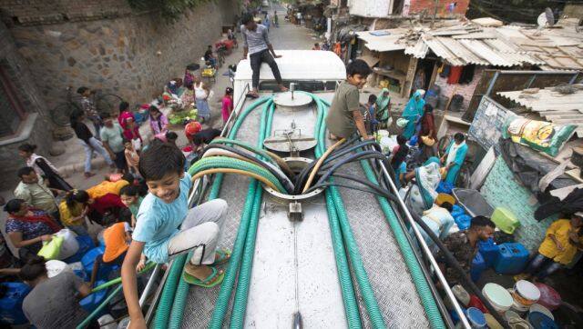 Residents use hoses to collect drinking water from a tanker truck during a hot summer day in New Delhi. AFP