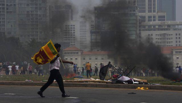 A Sri Lankan government supporter carries a national flag after attacking the anti-government protesters outside president's office in Colombo, Sri Lanka, Monday, 9 May. AP