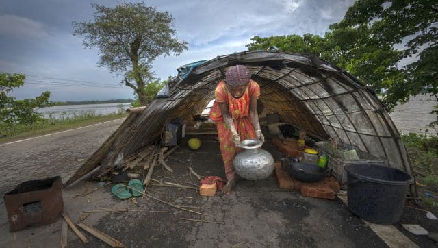 Obiron Nesa, a flood victim who lives in a temporary shelter on a road carries a pot filled with water at a village in Morigaon in Guwahati. AP