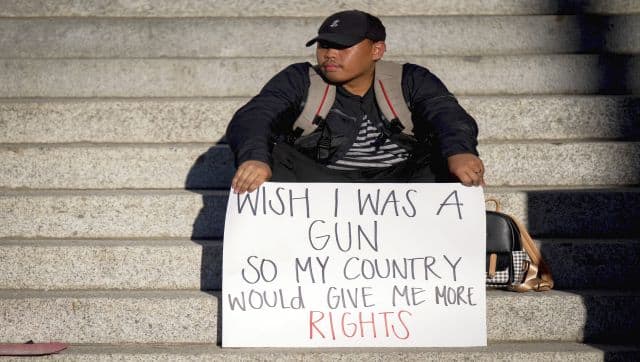 A pro-abortion supporter holds a sign comparing women's right and gun rights during a rally to protest the Supreme Court's decision to overturn Roe v Wade in downtown Riverside, California. AP