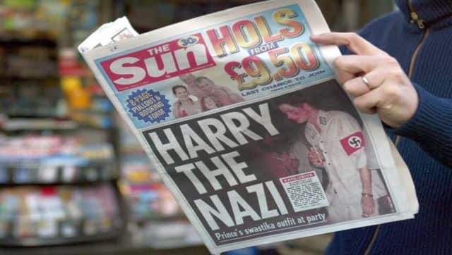 File image of a man reading the British tabloid The Sun featuring Harry wearing a khaki uniform with an armband emblazoned with a swastika, emblem of the German WWII Nazi Party. AFP
