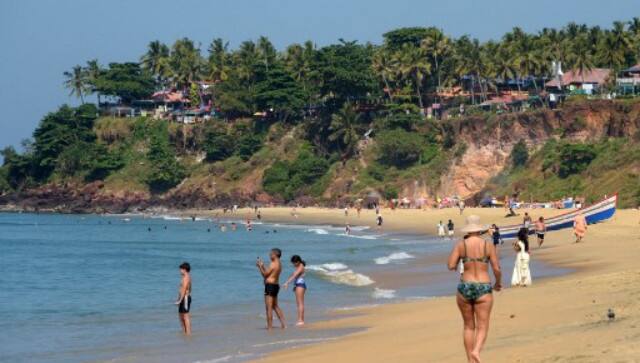 This photograph taken on January 10, 2018 shows tourists walking on Varkala beach in Indian the state of Kerala. AFP