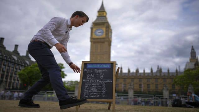 A betting company worker places a board showing odds for the exit of the British prime minister Boris Johnson outside of the Houses of Parliament, in London. AP