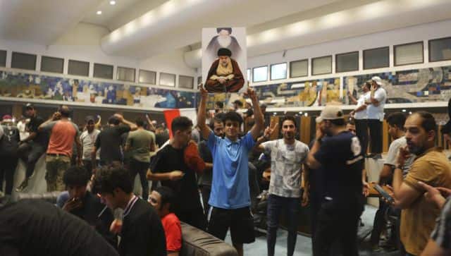 A Iraqi protester holds a poster of Shiite cleric Muqtada al-Sadr and his late father Mohammad Mohammad Sadeq al-Sadr as others breach the Parliament. AP