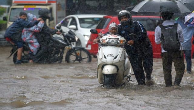 A man pushes his scooter through a flooded street during rain showers in Mumbai. AFP