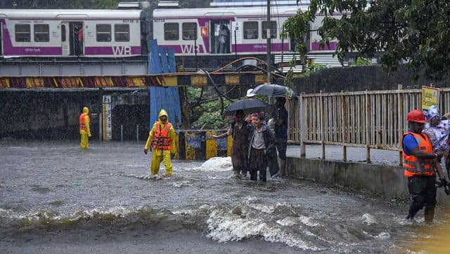 People wade through a water-logged street amid monsoon rains, near the closed Andheri Subway in Mumbai. PTI
