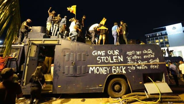 Protesters stand on a vandalised police water canon truck and shout slogans at the entrance to president's official residence in Colombo. AP 