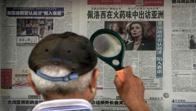 A man uses a magnifying glass to read a newspaper headline reporting on US House Speaker Nancy Pelosi's Asia visit, at a stand in Beijing. AP