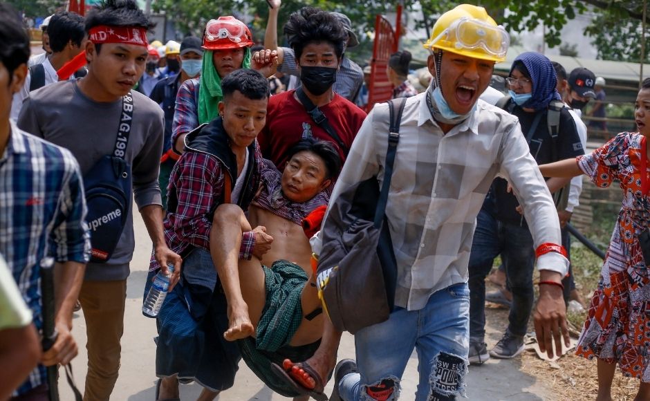 In this 14 March, 2021, file photo, anti-coup protesters carry an injured man following clashes with security in Yangon, Myanmar. (AP Photo, File)