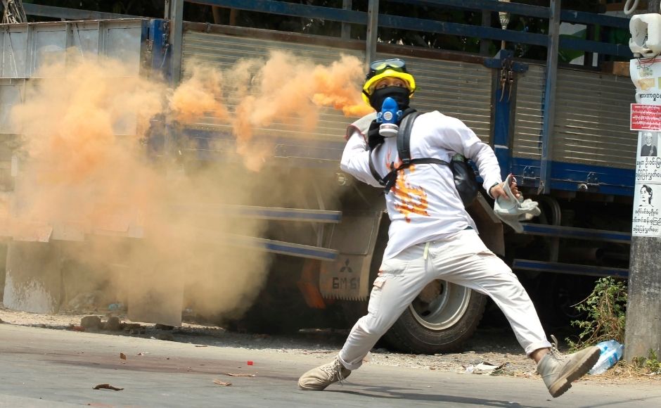 In this 27 March, 2021, file photo, an anti-coup protester throws a smoke bomb against police crackdown in Thaketa township Yangon, Myanmar. (AP Photo, File)