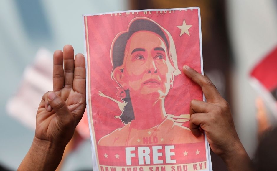 In this 8 February, 2021, file photo, Myanmar nationals living in Thailand hold pictures of Myanmar leader Aung San Suu Kyi gesture with a three-fingers salute, a symbol of resistance, as they protest in front of the Myanmar Embassy in Bangkok, Thailand. (AP Photo/Sakchai Lalit, File)