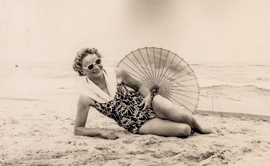 1625489504_Vintagephotoofwomanrestingonbeachinswimsuitwithumbrellaearly1960s.jpg