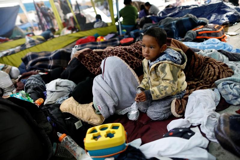 Central American caravan migrants wait in the cold as companions reach U.S.